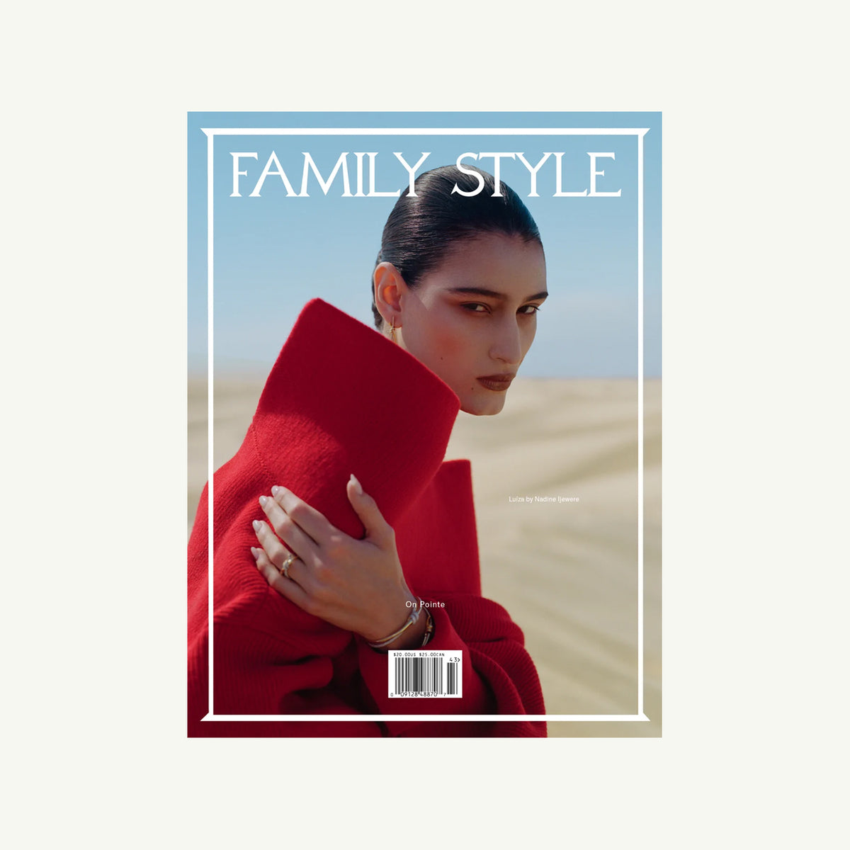 Woman in red coat on Family Style Magazine, standing in sandy landscape.