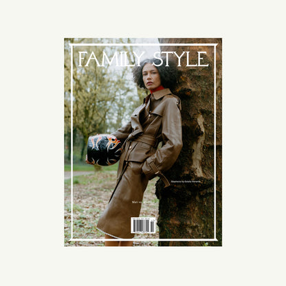 Woman in brown trench with black helmet, outdoors, holding Family Style Magazine by Family Style.