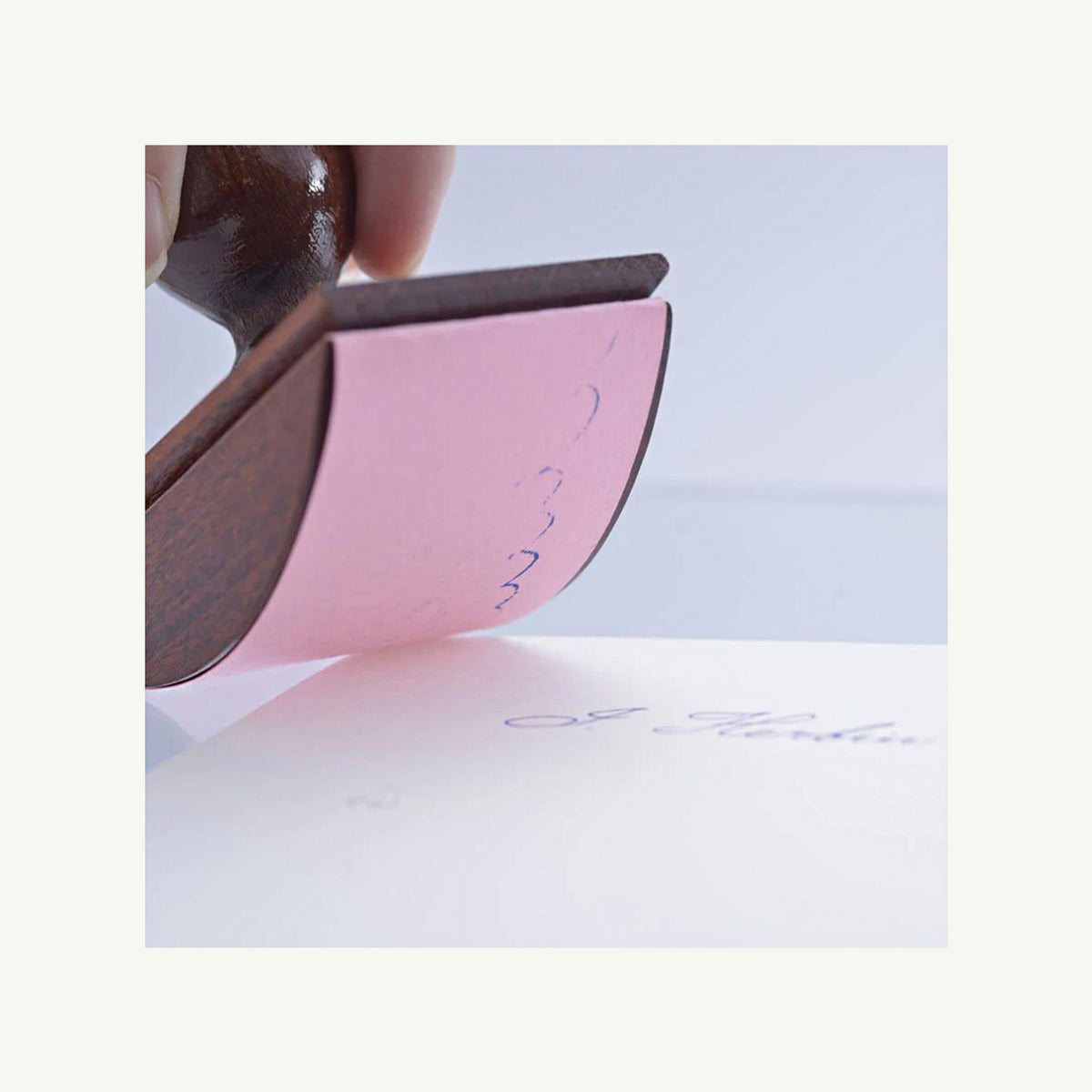 A hand using a Herbin Wooden Rocker-Style Ink Blotter on paper.