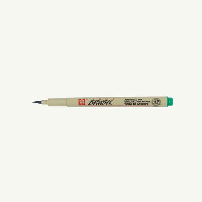 A Sakura Pigma Sketch Pen with a fine green cap tip rests horizontally on a plain background.