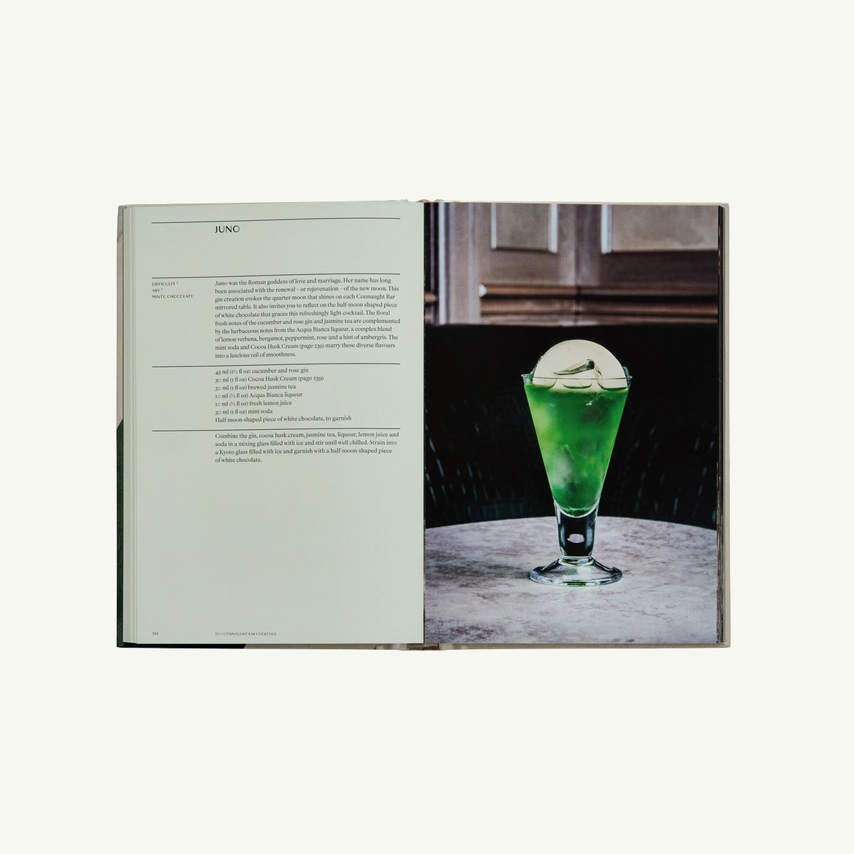 The Connaught Bar by Phaidon open with a green cocktail and round ice sphere on marble table.