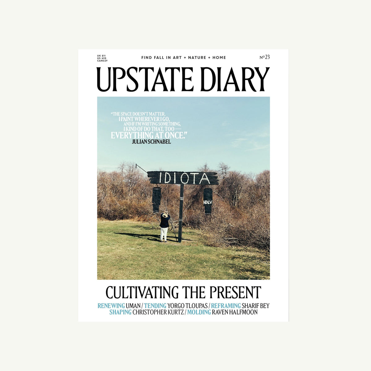 A person stands by a black Upstate Diary sign in a Catskills field under a blue sky.