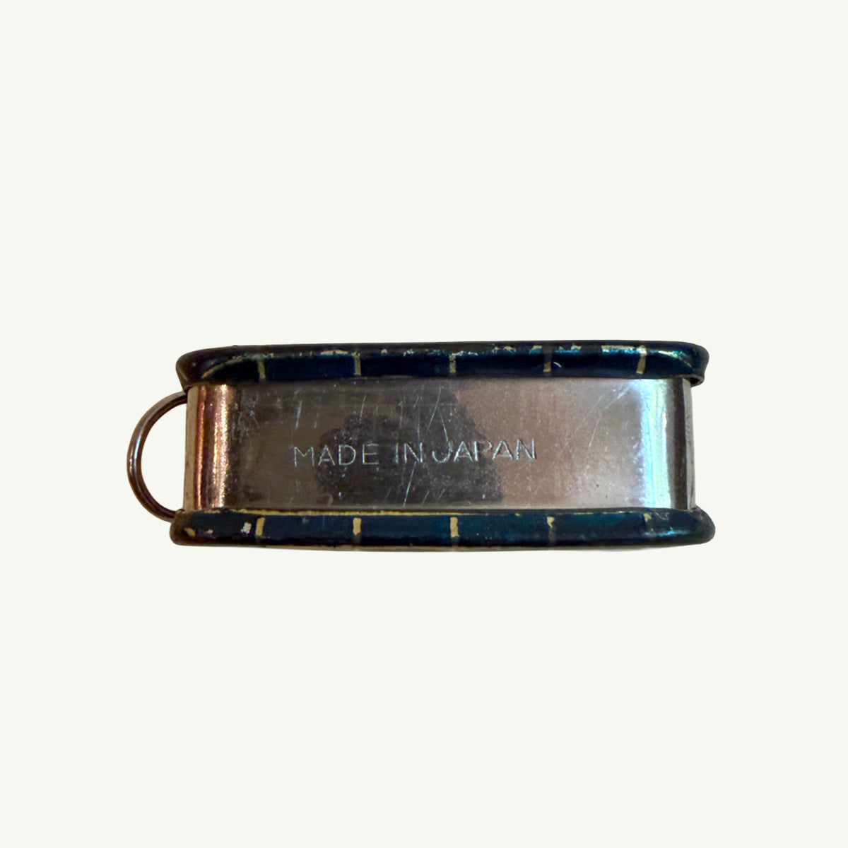 Mr. Boddington’s Studio Vintage Pocket Measuring Tape sits by a metal whistle on a plain surface.