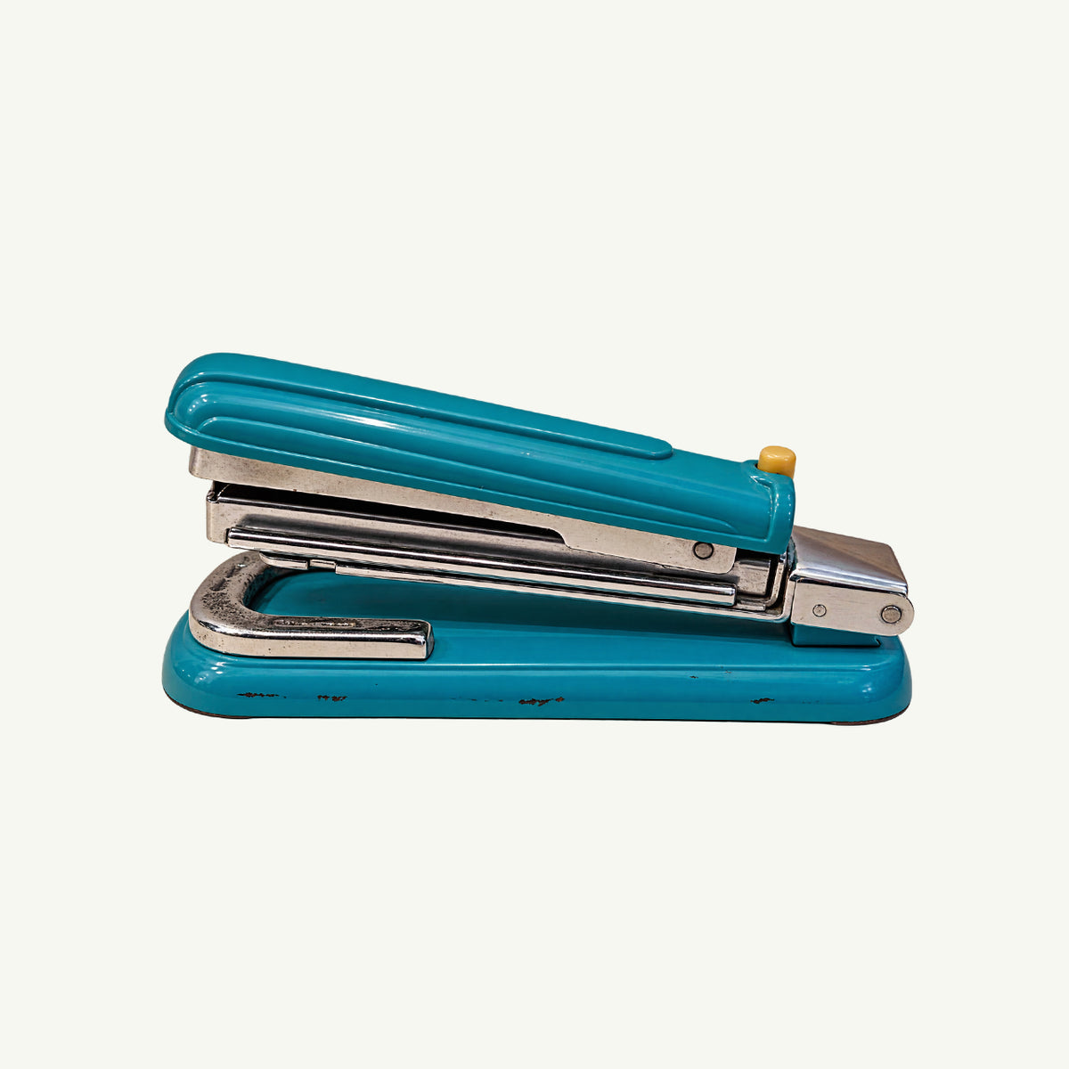 Vintage Yuen Chong 371 teal metal stapler with chrome accents and a yellow button.